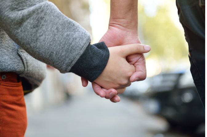 Boy and adult holding hands