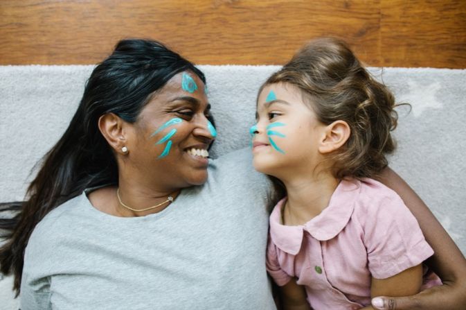 Child and adult smiling at each other with face paint