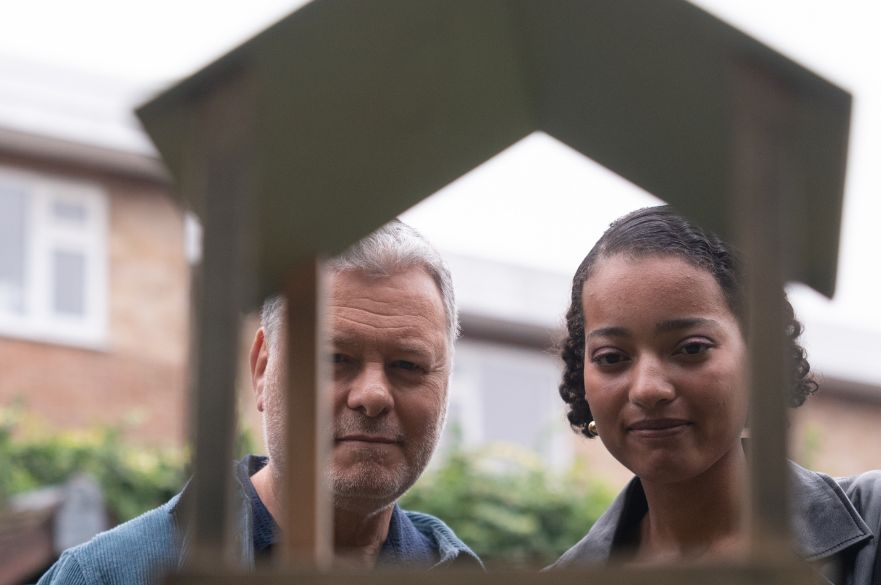 Man and young woman looking at a bird feeder in a garden