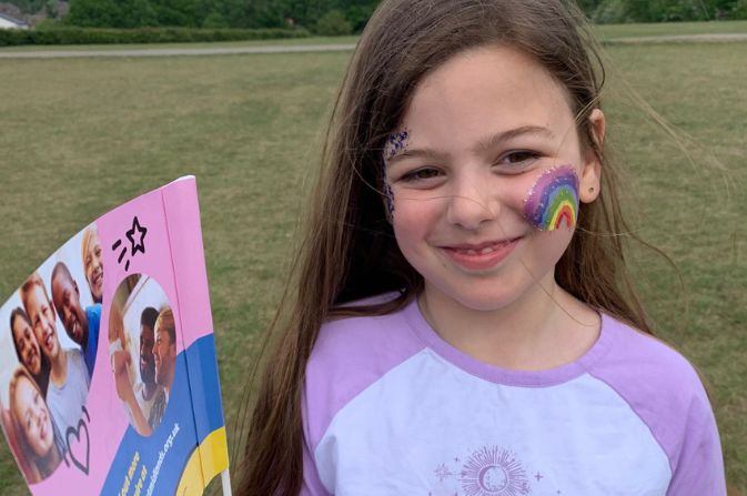 Girl at foster carer's family event smiling with a flag