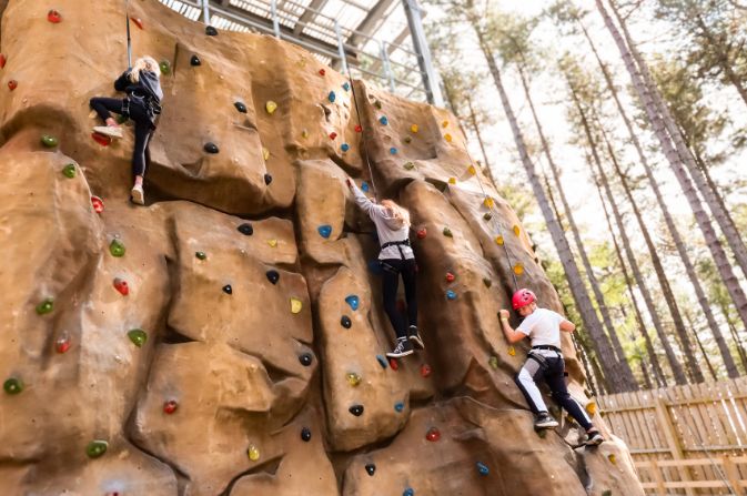 Children climbing a wall with safety equipment