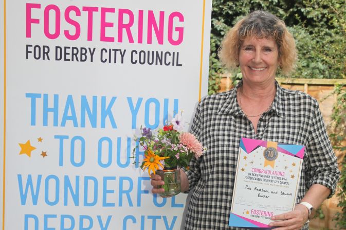 Pat holding flowers and a certificate